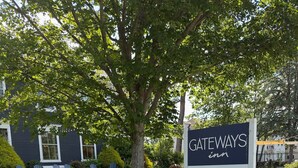 A sign for Gateways Inn advertising mat and mimosa services, with a garden area in the background.