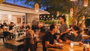 An outdoor dining area with tables and chairs, a waiter, and guests. - Alcazar Palm Springs (Palm Springs)