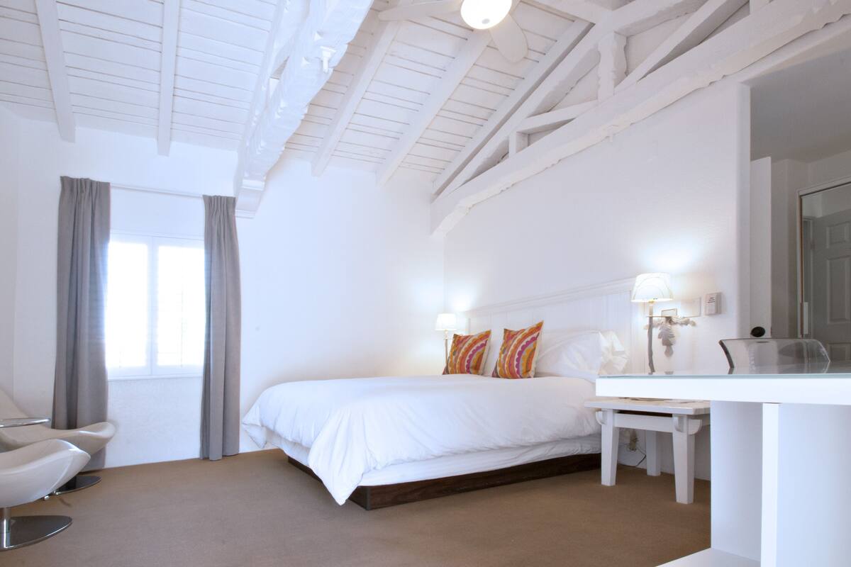 Un dormitorio con una cama, un escritorio, una silla y un ventilador de techo.