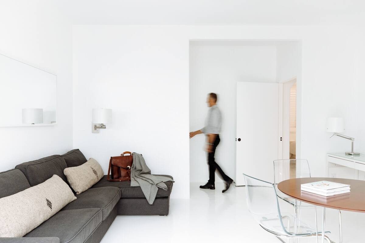 Una sala moderna con un sofá seccional gris, un bolso de cuero marrón y una mesa de centro de vidrio.