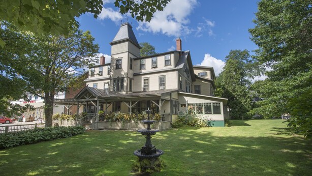 A large, historic house with a prominent tower, a covered porch, and a well-maintained lawn with a fountain. - Norwich Inn (Norwich)