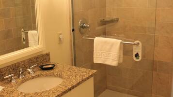 Un baño con dos lavamanos, un espejo y una ducha con puertas de vidrio.
