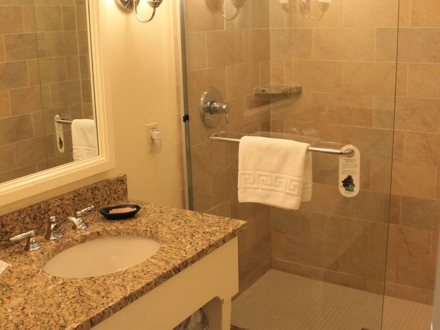 Un baño con dos lavamanos, un espejo y una ducha con puertas de vidrio.