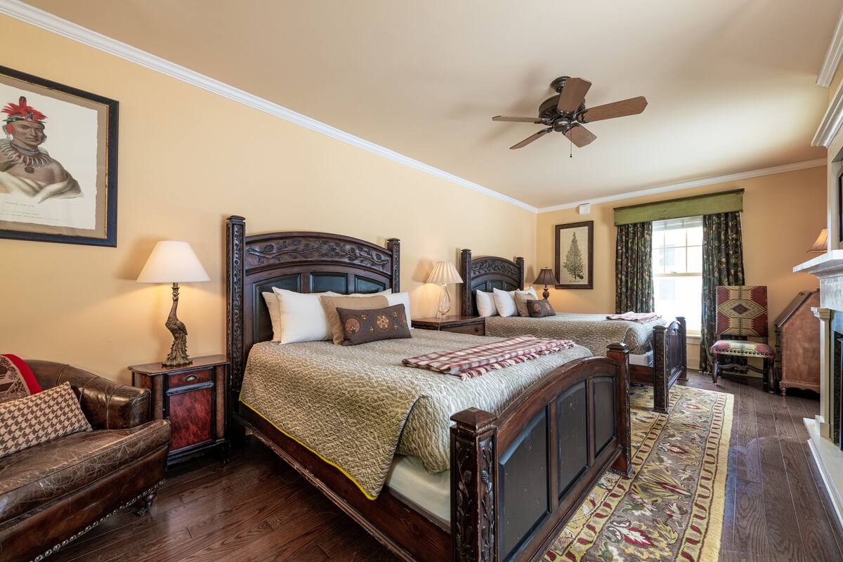 A traditional bedroom with a large bed, two bedside tables, a ceiling fan, and a framed picture on the wall.