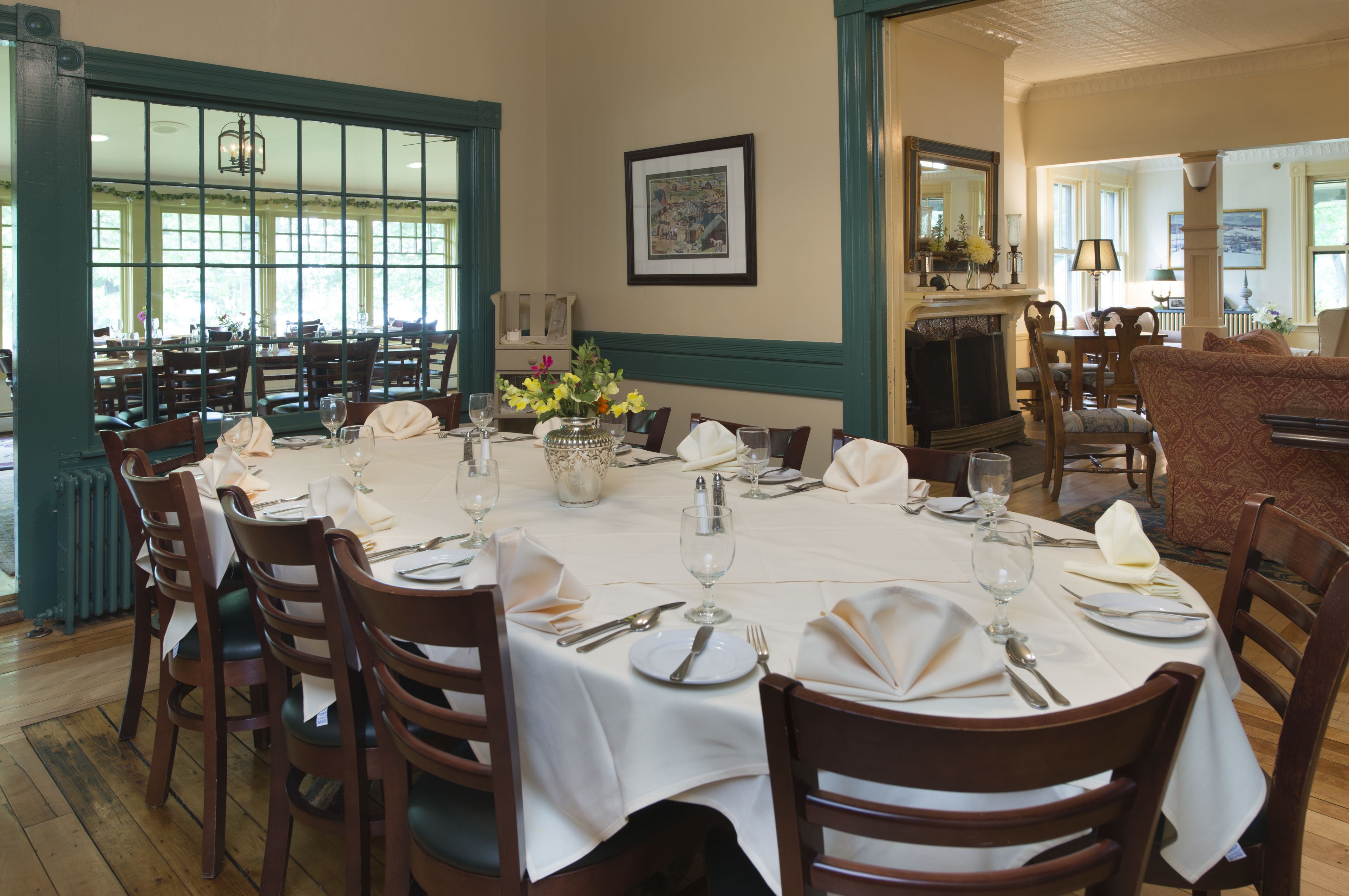 A dining area with a round table set for six, surrounded by wooden chairs.