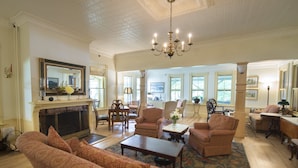 A spacious living room with a fireplace, multiple seating areas, and a chandelier. - Norwich Inn (Norwich)