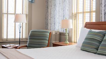 Habitación de hotel con una cama, dos sillas, una mesa y dos lámparas.