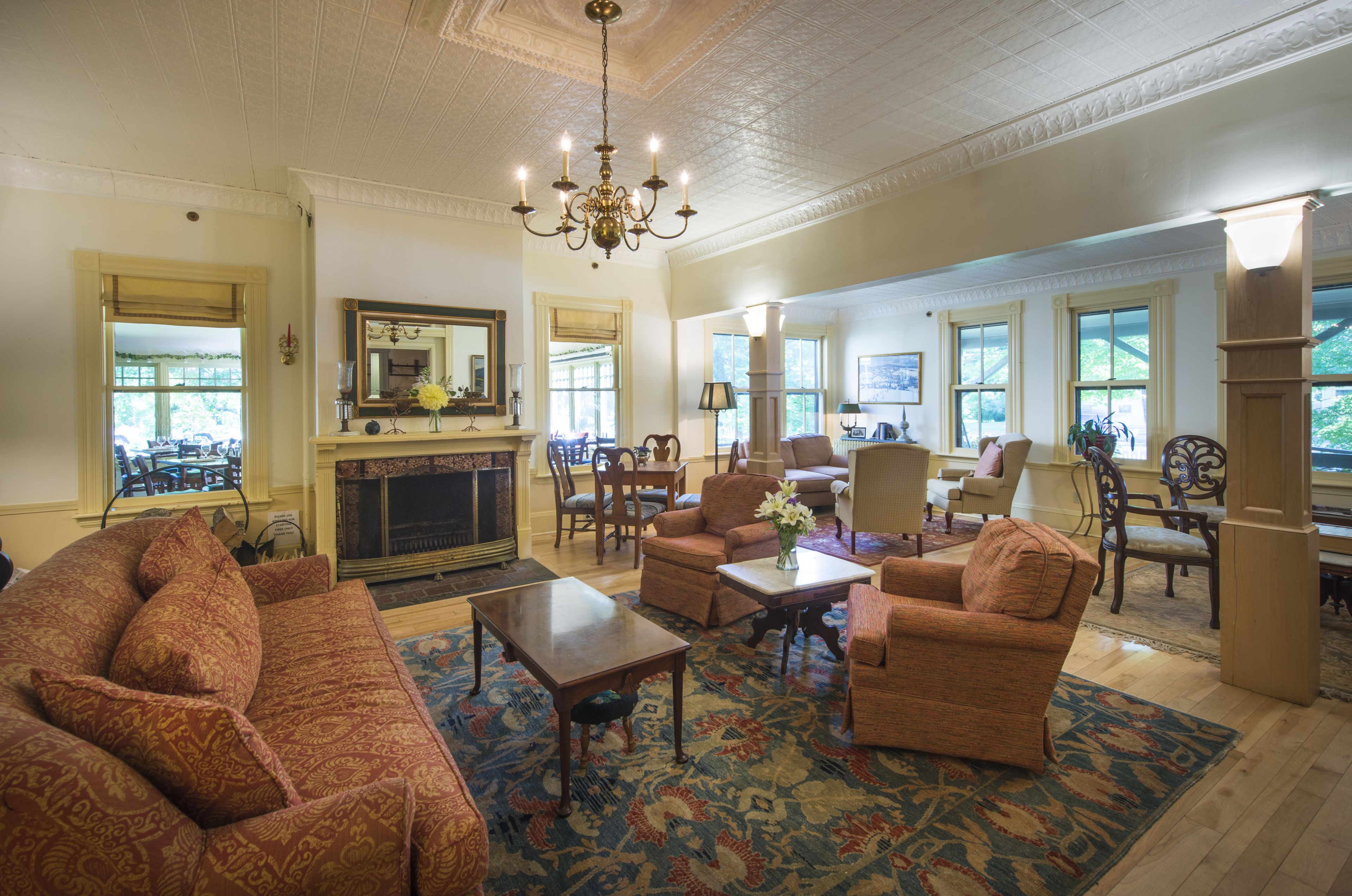 A spacious living room with a fireplace, comfortable seating, and large windows.