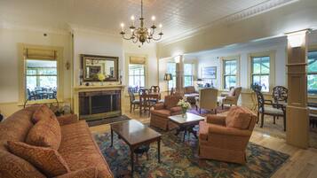 A spacious living room with a fireplace, comfortable seating, and large windows.