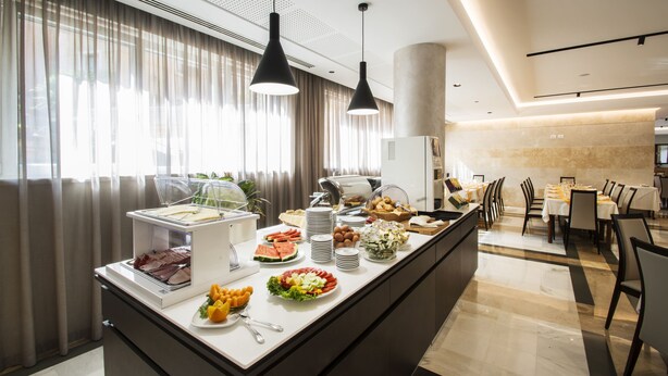 A buffet setup with various food items and a dining area with tables and chairs. - Hotel Bisesti (Garda)