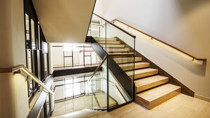 A modern staircase with glass railings and wooden steps. - Hotel Bisesti (Garda)
