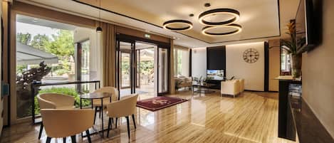 A modern hotel lobby with a polished wooden floor, a reception desk, and a seating area with chairs and a table.