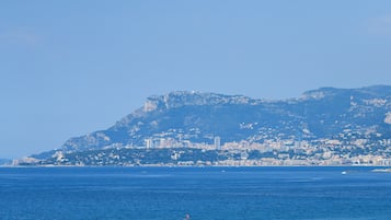 Un paisaje urbano costero con una montaña destacada al fondo.