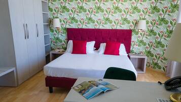 A bedroom with a bed, a desk, a lamp, and a wardrobe.