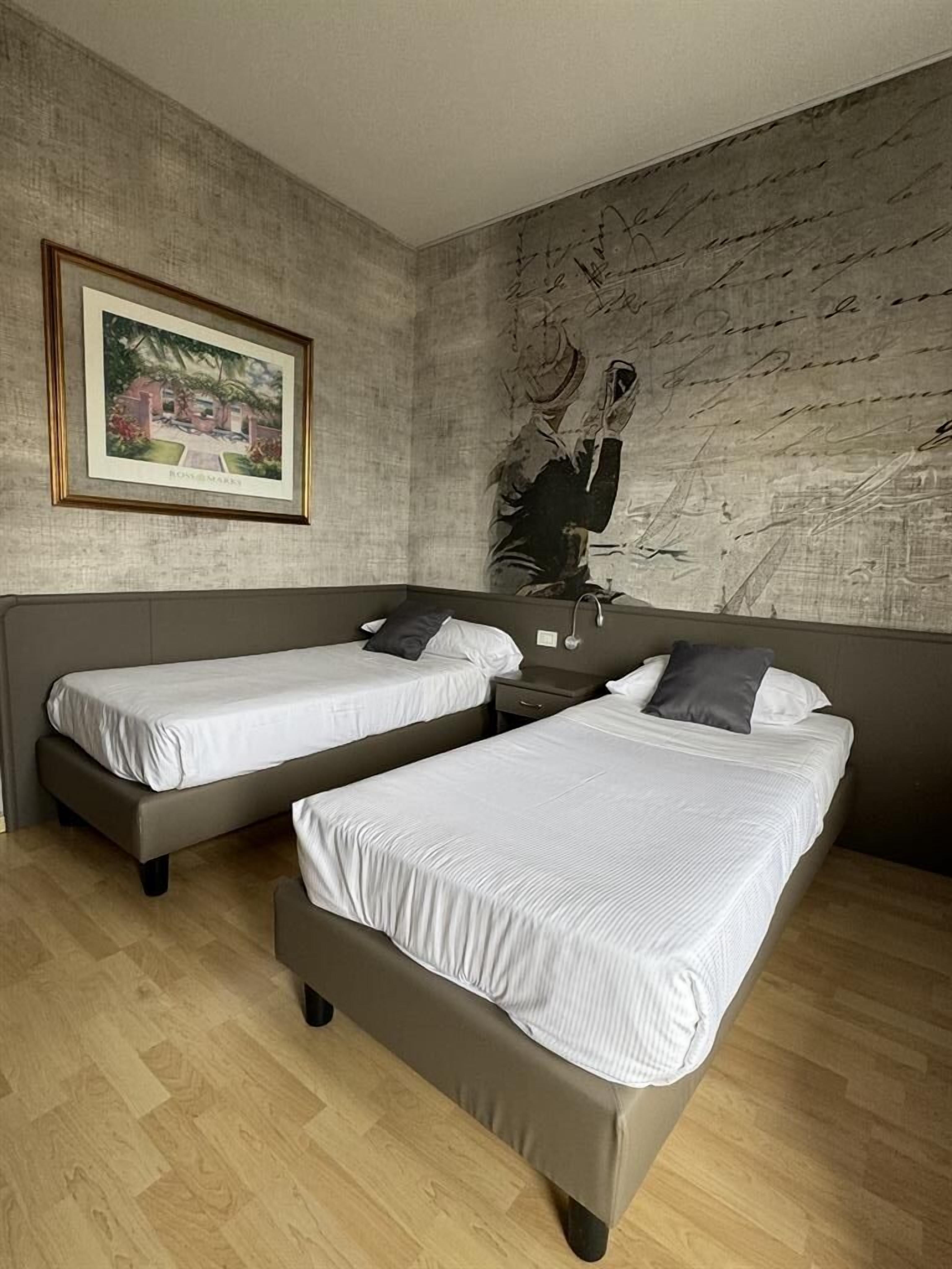 A bedroom with two single beds, a nightstand, a framed picture, and a textured wall.