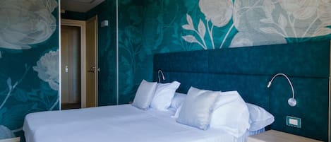 Une chambre à coucher avec un grand lit, une table de chevet et un mur recouvert d’un papier peint à motifs floraux.