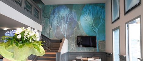 Un moderno vestíbulo de hotel con una escalera, una zona de estar y un gran mural en la pared.