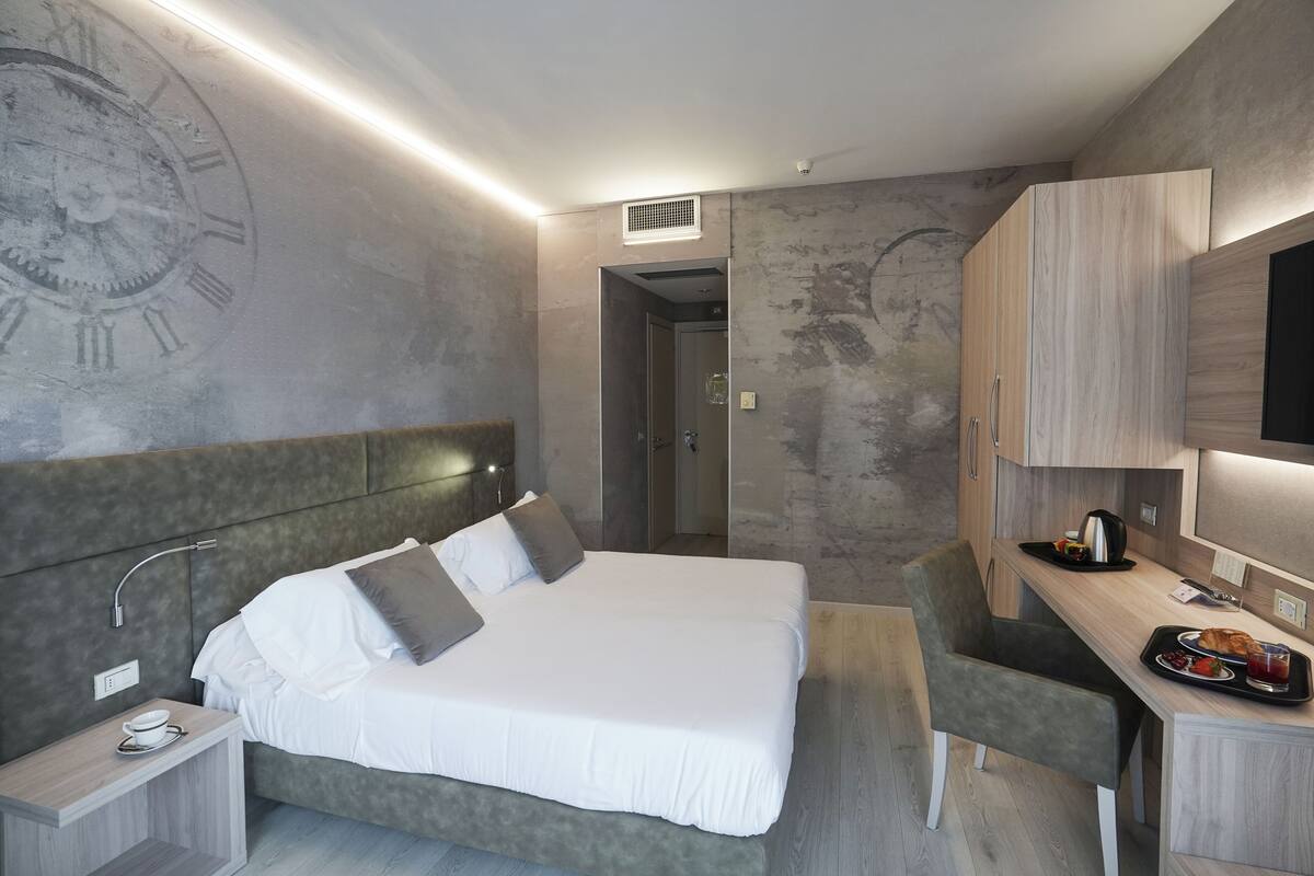Une chambre d’hôtel moderne, dotée d’un grand lit, d’un bureau et d’une télévision.