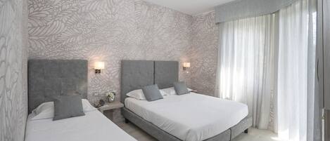 Una habitación de hotel moderna con dos camas, un ventanal con cortinas y una pared con diseño.