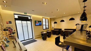 Um lobby moderno de hotel com balcão de recepção, área de estar e tela de televisão.