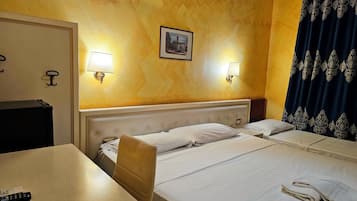 Ein Hotelzimmer mit zwei Betten, einem Schreibtisch, einem Stuhl, einer Lampe und einem Bild an der Wand.