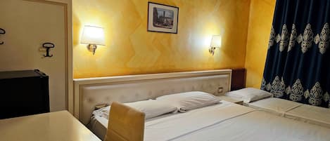 A hotel room with two beds, a desk, a chair, a lamp, and a picture on the wall.