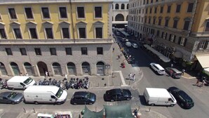 A multi-story hotel with a yellow facade, large windows, and a central courtyard with parked vehicles and pedestrians. - Ferrari (Rome)