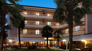 A multi-story hotel with balconies, outdoor seating, and palm trees. - Imperial (Garda)