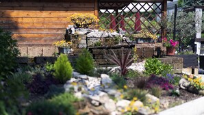 A garden with various plants and flowers, a wooden fence, and a stone structure. - Imperial (Garda)