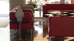 A modern hotel lobby with red seating, a patterned vase, and a view of the outdoors. - Imperial (Garda)