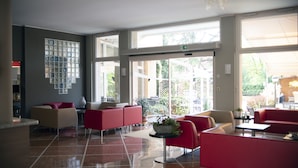 A spacious lobby with red and beige seating, large windows, and a tiled floor. - Imperial (Garda)