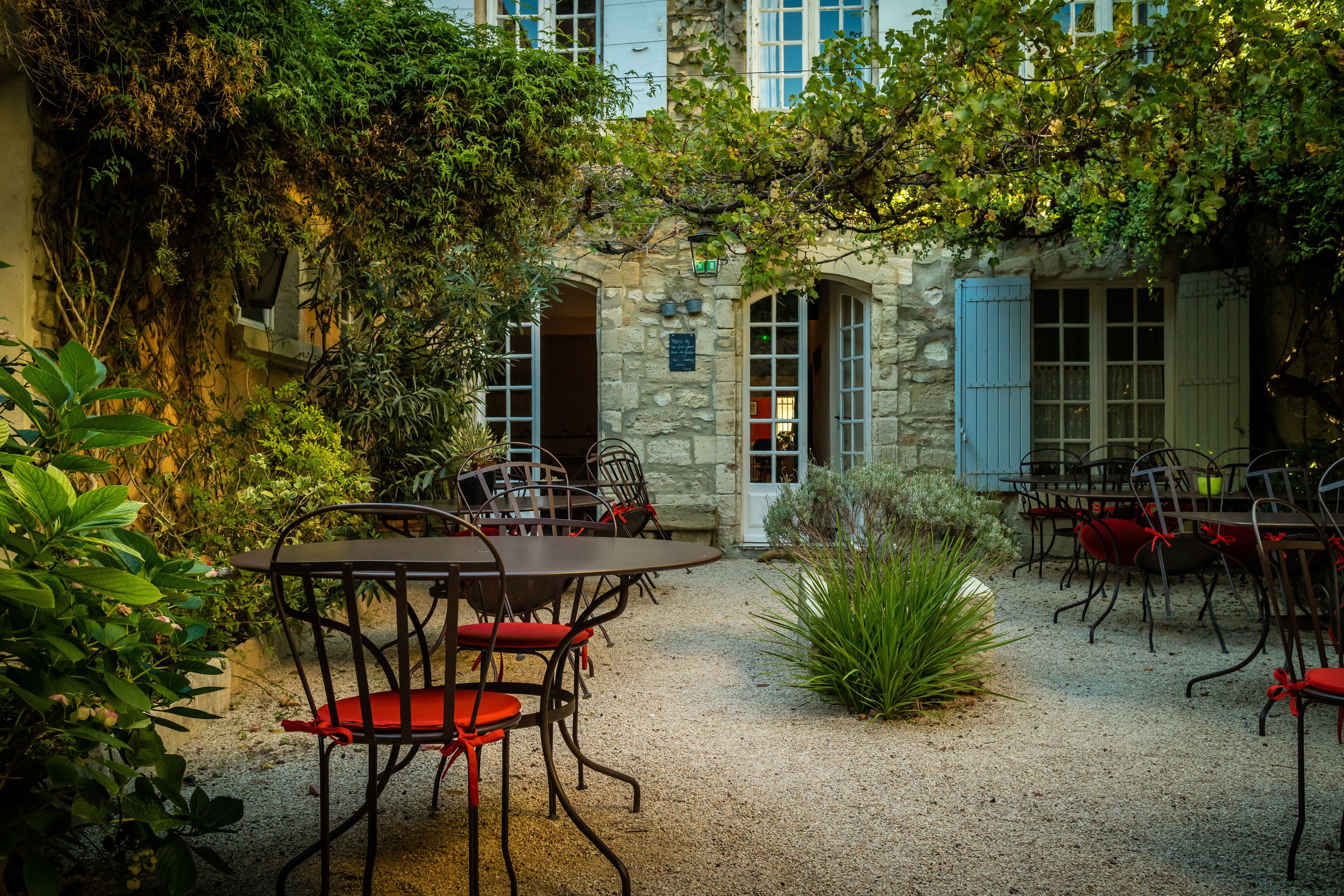 An outdoor patio with stone walls, a gravel ground, and metal tables and chairs.