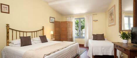 Habitación de hotel con dos camas, televisión y ventana con cortinas.