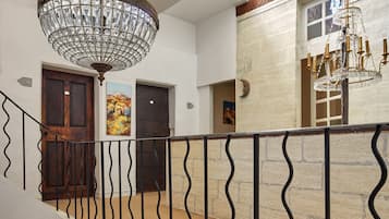 Un interior de varios niveles con una escalera, candelabros y obras de arte.