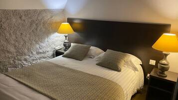 Une chambre d’hôtel avec un lit, deux lampes de chevet, un mur à motifs et une tête de lit sombre.