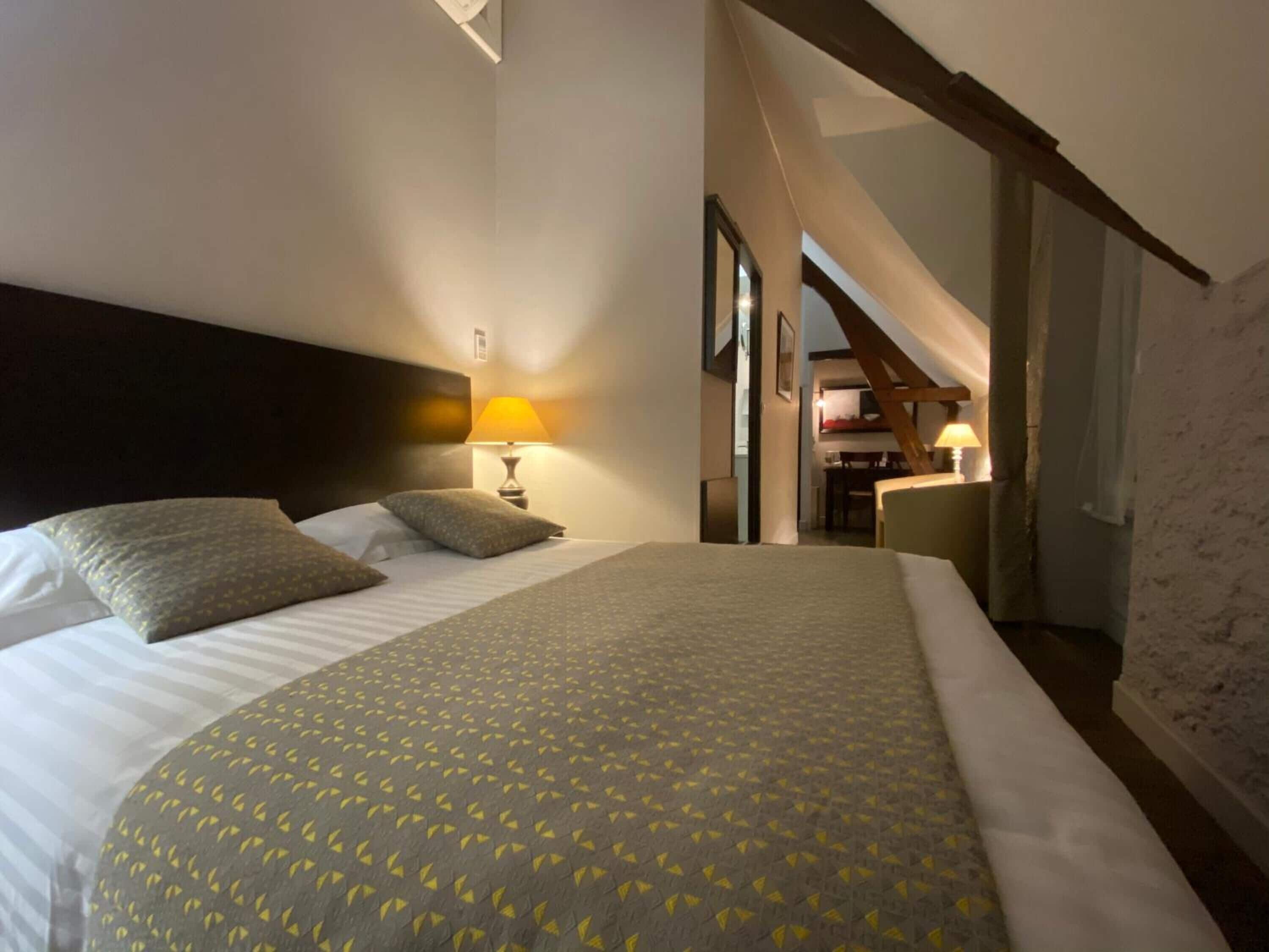 Une chambre d’hôtel avec un lit, une table de chevet, une lampe et une vue sur la cuisine.