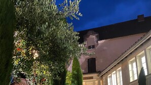 A paved pathway leading to a building with a stone facade, surrounded by well-maintained greenery and a clear night sky. - LOGIS Hostellerie des Ducs (Duras)