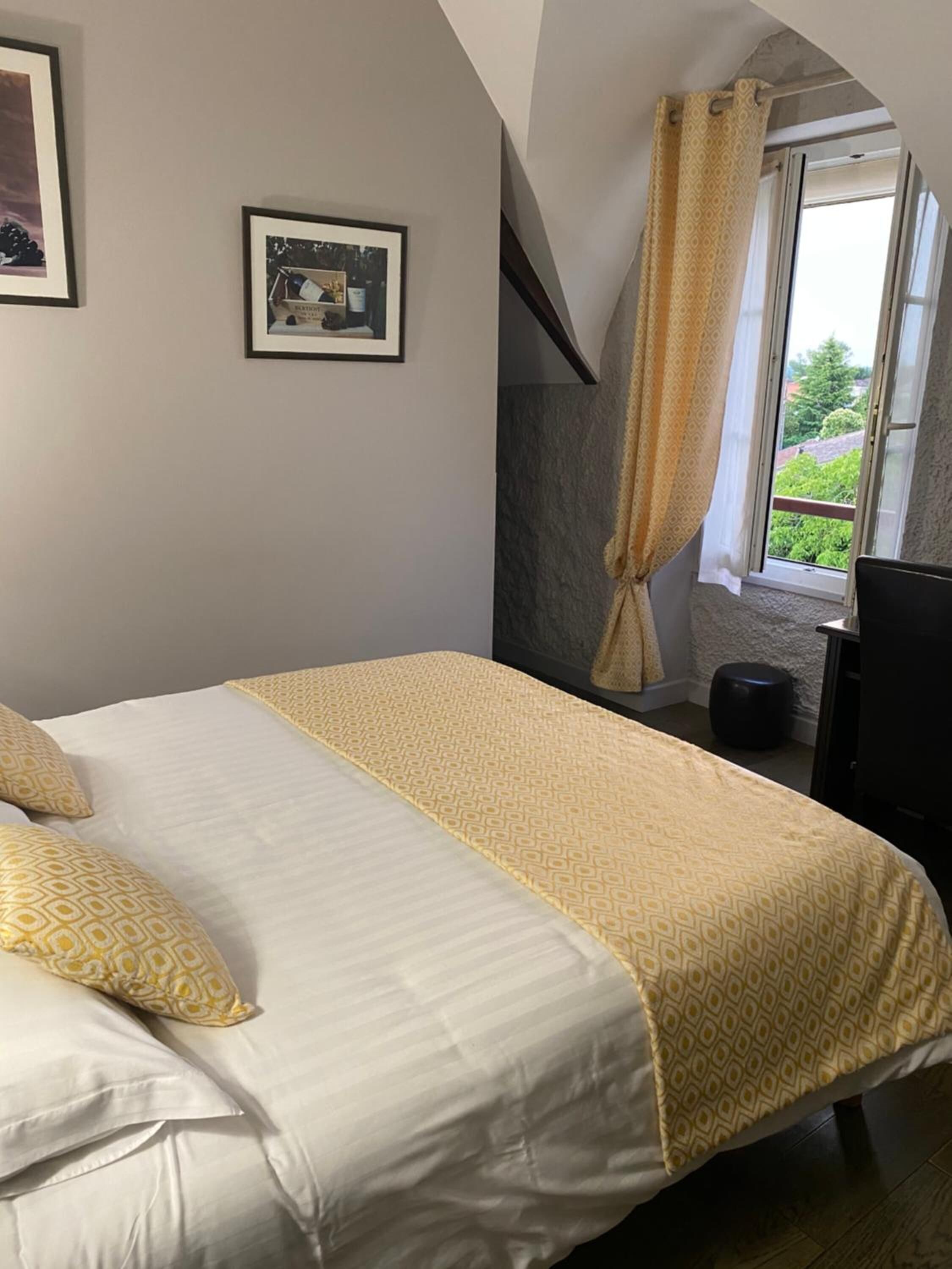 Quarto com uma cama, uma janela com cortinas e um quadro na parede.
