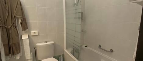 A bathroom with a toilet, a glass-enclosed shower, and a bathtub.