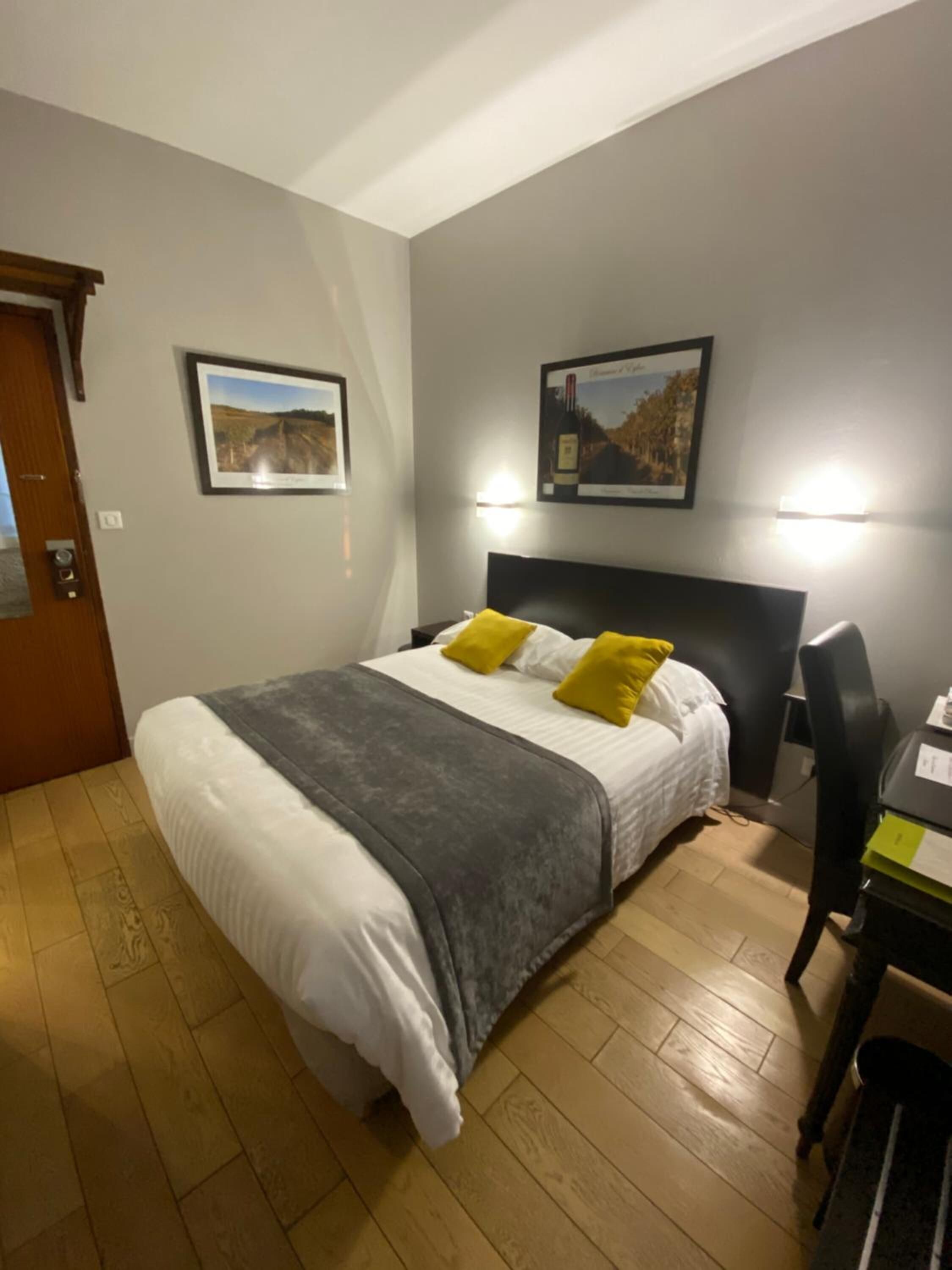Une chambre à coucher avec un lit, deux oreillers, un bureau et deux tableaux encadrés accrochés au mur.