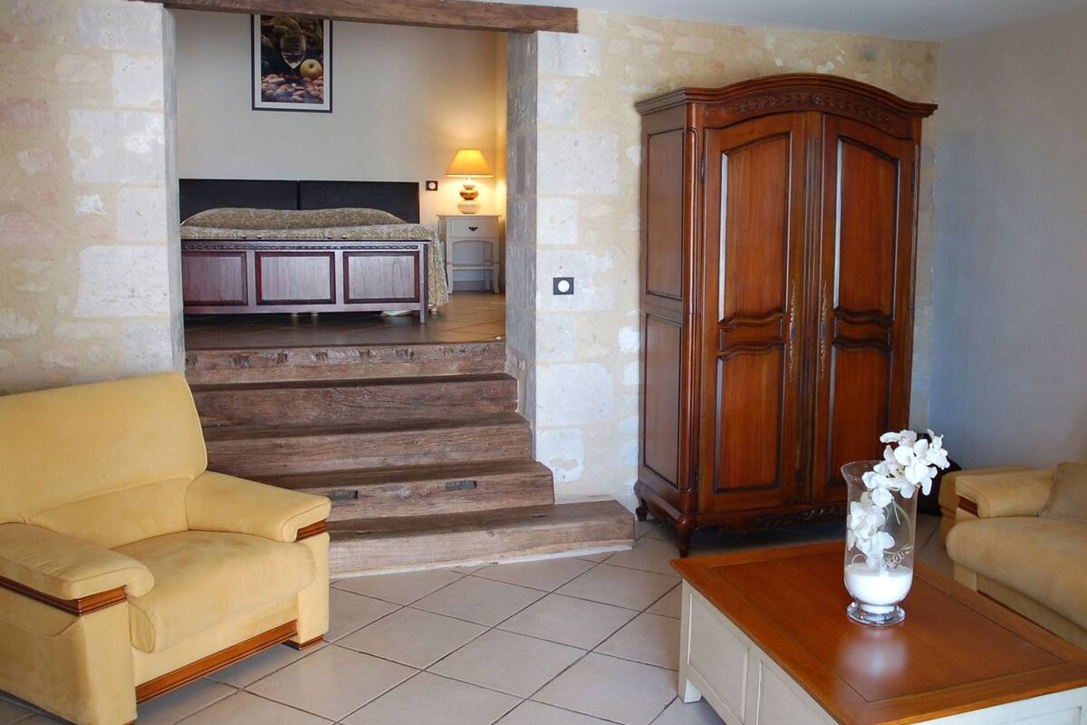 Um quarto com uma cama, um guarda-roupa de madeira, um sofá amarelo e uma mesa de centro.