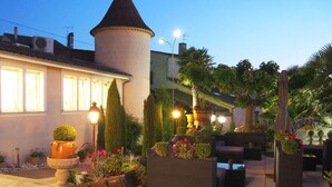 A courtyard with a tower, outdoor seating, and potted plants. - LOGIS Hostellerie des Ducs (Duras)