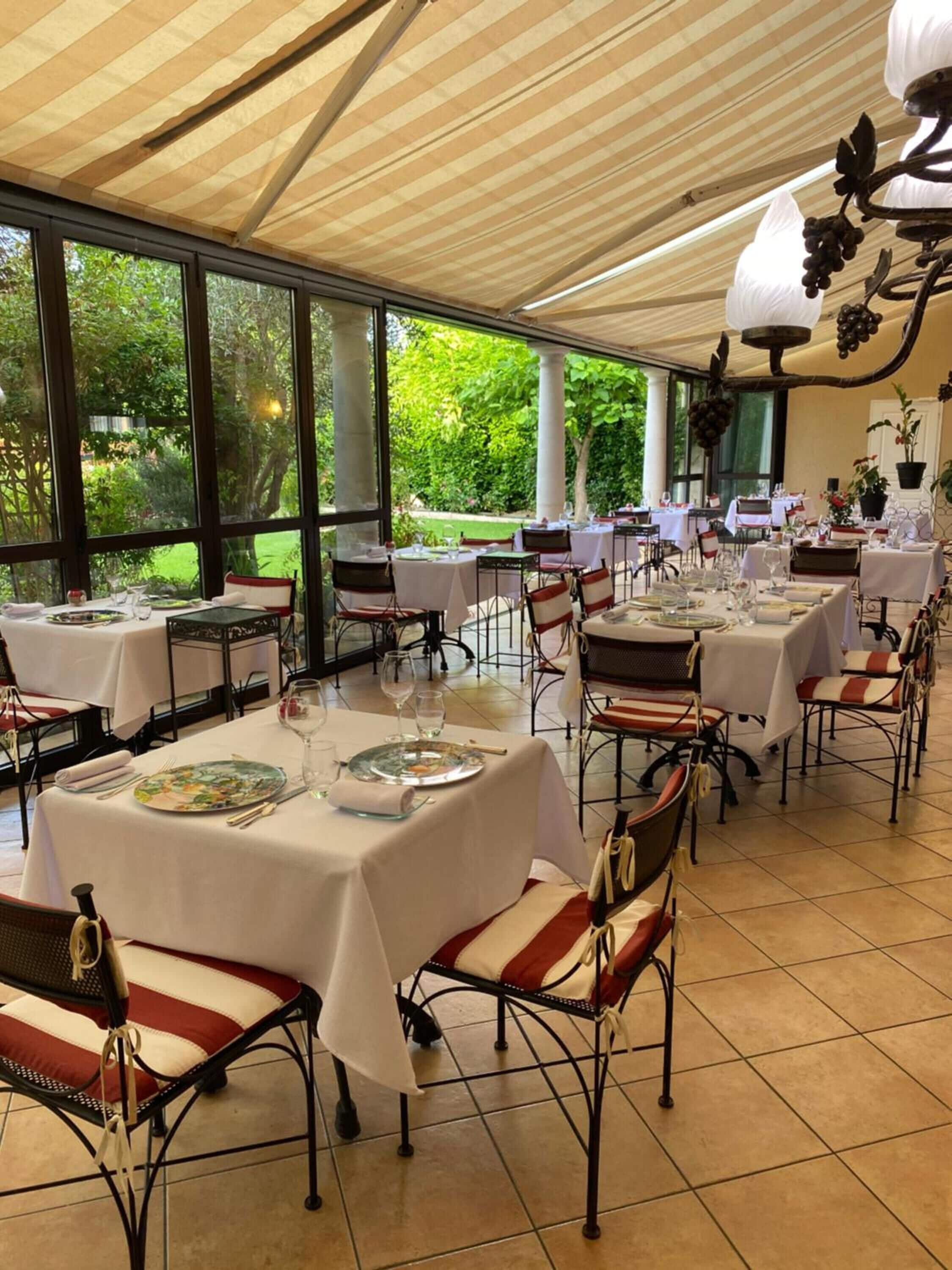 Una sala ristorante con tavoli apparecchiati, ampie finestre e un soffitto a righe.