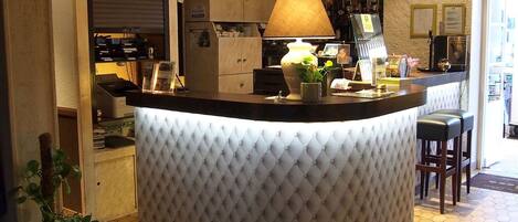 A bar area with a tufted counter, a lamp, and a coffee machine.