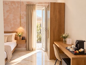 Quarto de hotel com cama, mesa de cabeceira com telefone, escrivaninha com cafeteira e vista para o exterior.