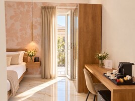 Habitación de hotel con cama, mesita de noche con teléfono, escritorio con cafetera y vistas al exterior.