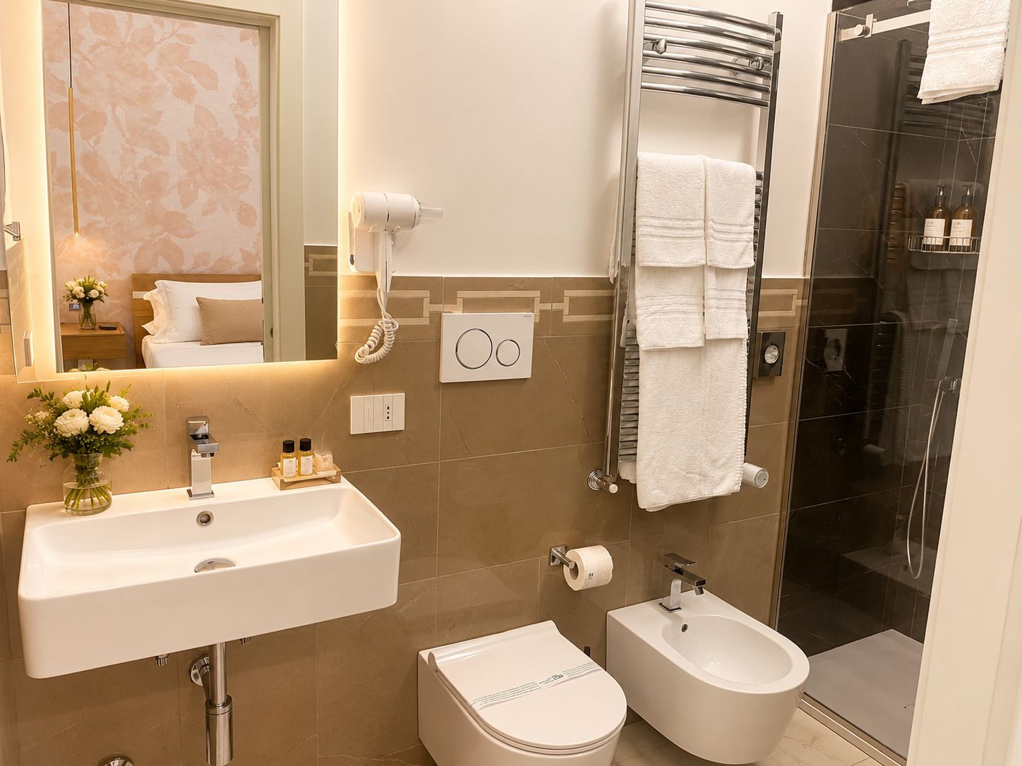 A modern bathroom with a sink, bidet, toilet, and a glass-enclosed shower.