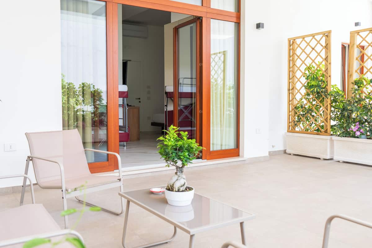 Un espace extérieur moderne aménagé avec des sièges et une porte vitrée donnant sur la cuisine.