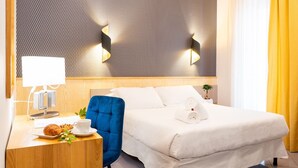 A hotel room with a bed, a bedside table with a lamp, a chair, and a small table with a croissant and a cup. - Diana Pompei (Pompei)