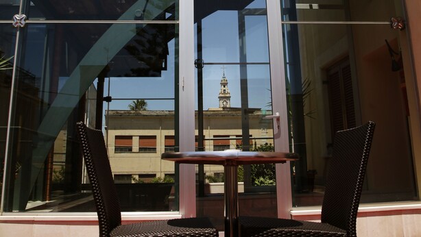 A modern building with large glass windows, a staircase, and a table with two chairs outside. - Diana Pompei (Pompei)